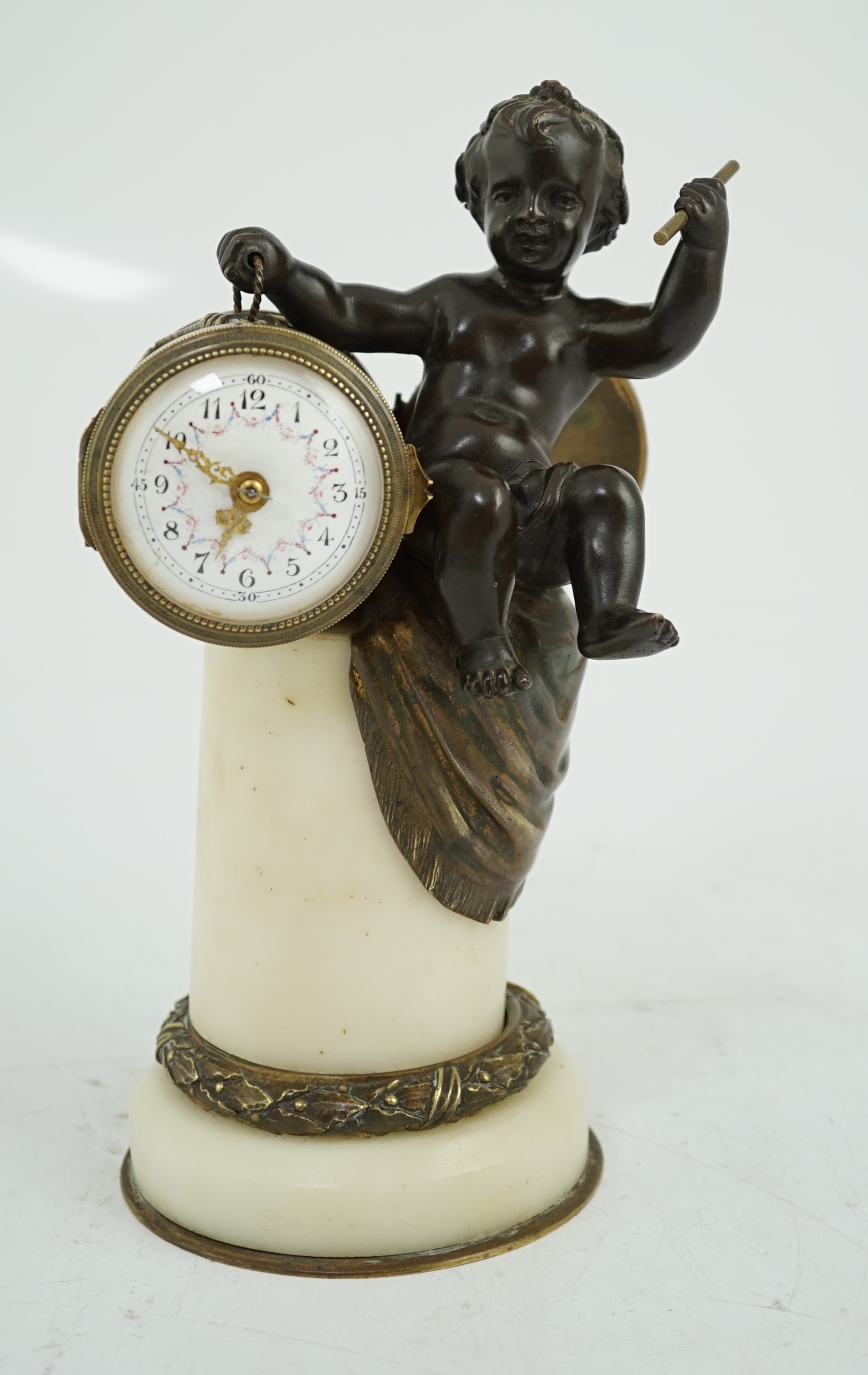 An early 20th century French eight day bronze and ormolu desk timepiece modelled as a putto banging upon a drum, with floral enamelled dial and white marble plinth, 12cm wide, 22.5cm high. Condition - good